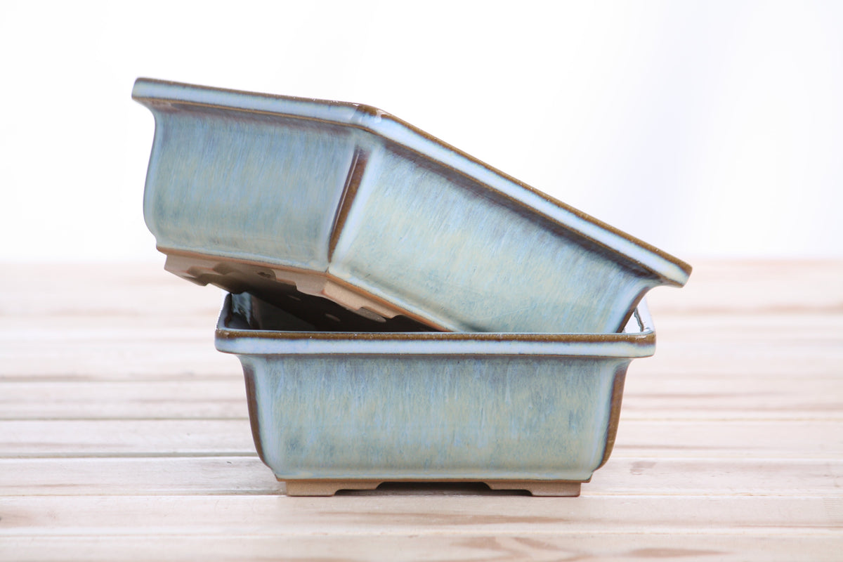 Two square ceramic bonsai pots stacked, glossy finish, light blue color, wooden surface backdrop