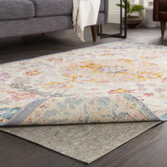 Mohawk Dual Surface Pad with a printed design, grey felt underneath, set in a living room with a sofa and throw blanket visible.