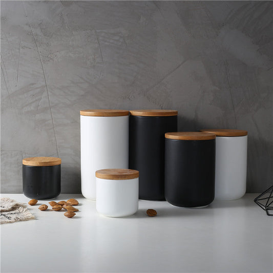 Kitchen ceramic wooden lid sealed storage jars in white and black with wooden lids on a gray countertop.