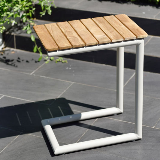 Simple C-shaped side table with wooden slats and white legs, outdoor setting.