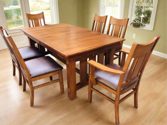 A Mission Quarter Sawn Oak dining table set with four chairs in a room with wood flooring and light green walls.