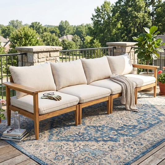 A Terassi Outdoor Acacia Wood 4 Seater Sofa with light beige cushions on a wooden deck under a clear sky.