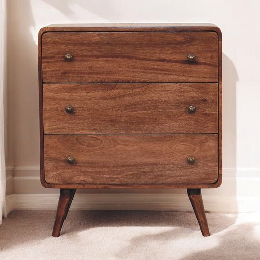 Solid wood chest with three drawers and brass handles, placed against a cream wall and light carpet
