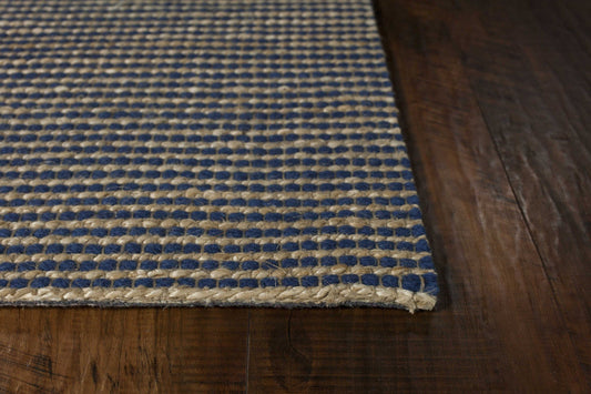 A close-up of a blue and beige hand-woven wool and jute area rug on a wooden floor