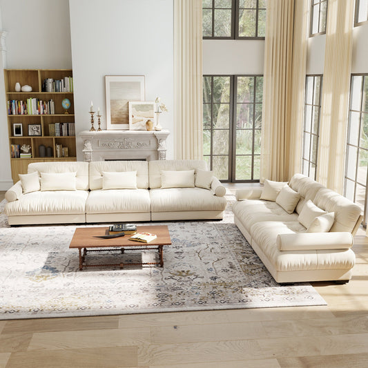 A living room with light beige velvet modular sofa set and a wooden coffee table on a patterned area rug.