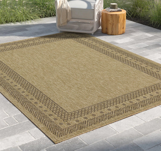 Rectangular jute indoor/outdoor rug with tribal border, brown in color, placed on a paved patio.