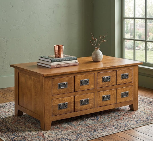 Mission 8 Drawer Coffee Table with wooden drawers and metal handles, placed on a patterned rug next to a window with green walls.