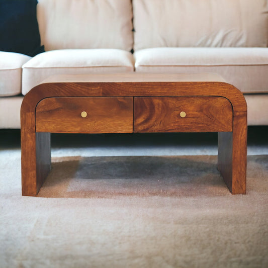 Solid wood coffee table with two drawers, chestnut brown finish, on a light carpet with a sofa in the background.