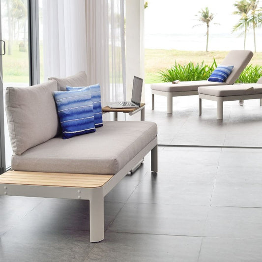 Light grey sofa with white and wood accents, blue textured throw pillows, glass doors, and outdoor setting