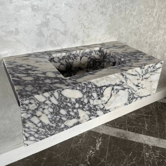 ```json
{ "alt": "Calacatta Viola Marble Bathroom Vanity Sink Handcrafted Custom Contemporary Style, cream and black veined marble, against grey wall and floo