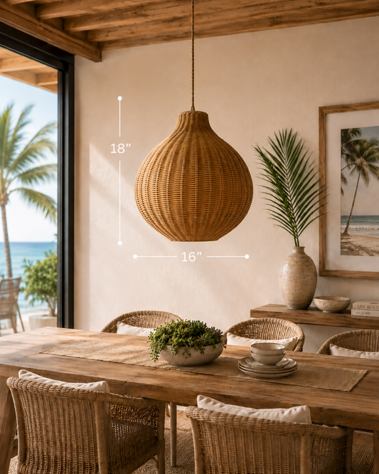 ```json
{"alt":"Coconut Groove Pendant hanging from a cord, made of natural woven material, in a dining area with a wooden table and chairs, overlooking a beach