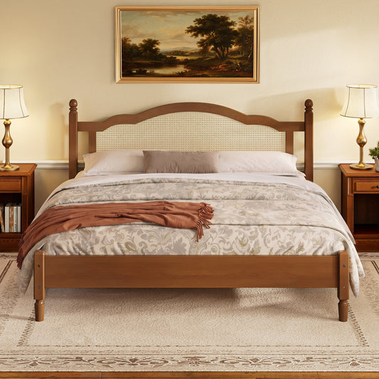 A wooden platform bed with a rattan headboard, covered with patterned bedding and a throw, positioned in a bedroom with side tables, lamps, and framed landscape painting.