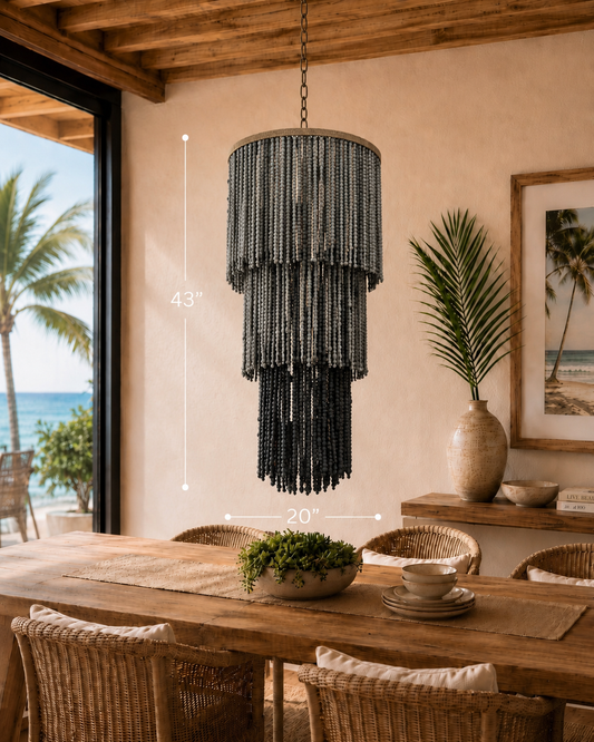Shadow Tide Chandelier with dark beaded tiers, hanging above a wooden dining table in a beachside setting