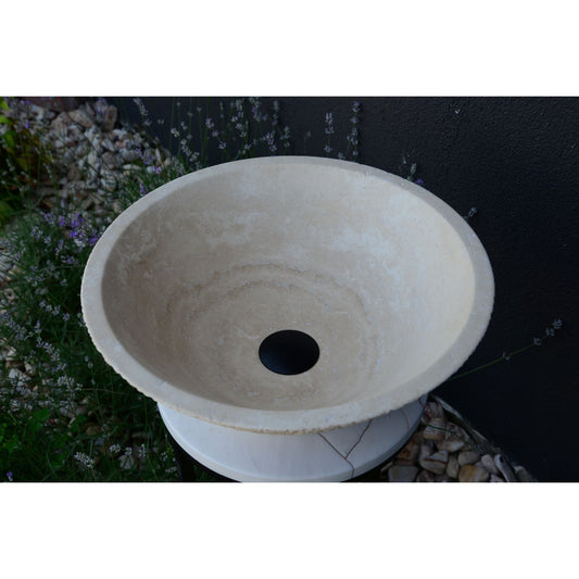Travertine Vessel Sink in light beige with natural stone texture, placed outdoors with lavender and pebbles.