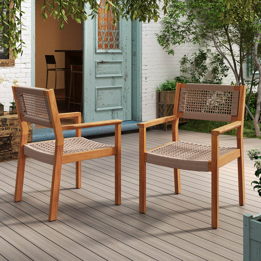 Two wooden chairs with woven seats on a wooden deck outside a building with plants.