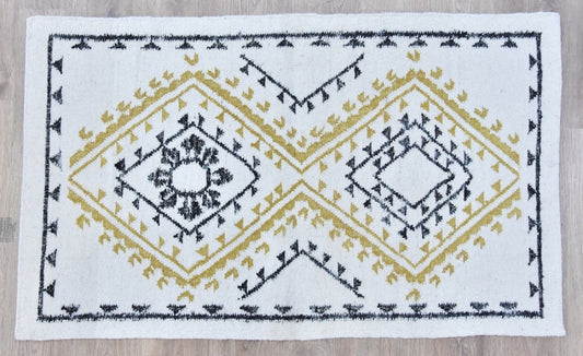 A white rug with black and mustard yellow geometric patterns.
