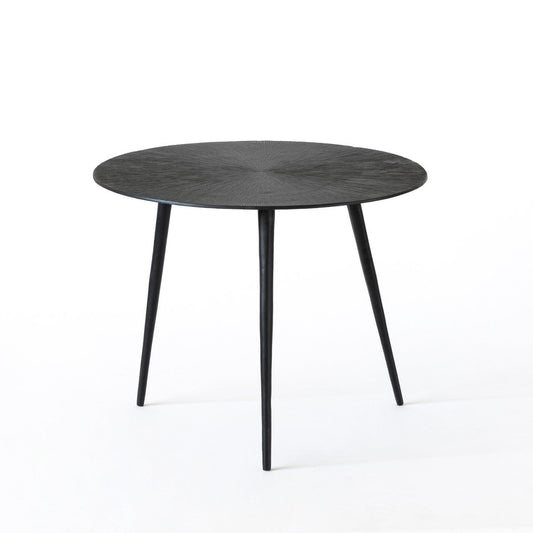 Round black table with textured surface and tapered legs.