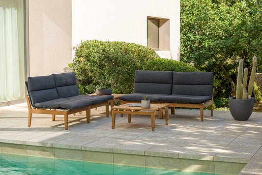 Teak corner sofa set with dark gray cushions, sitting on patio near pool, outdoor setting with greenery.