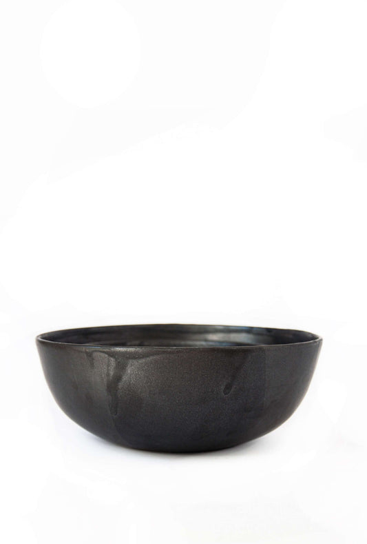 A matte black stoneware salad bowl set against a white background.