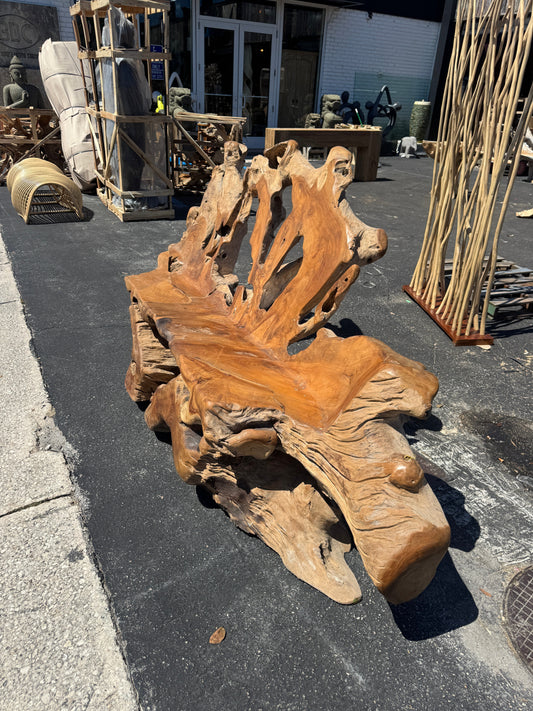Teak root sofa XXL (D) on a street with rustic wood surroundings and outdoor goods in the background.