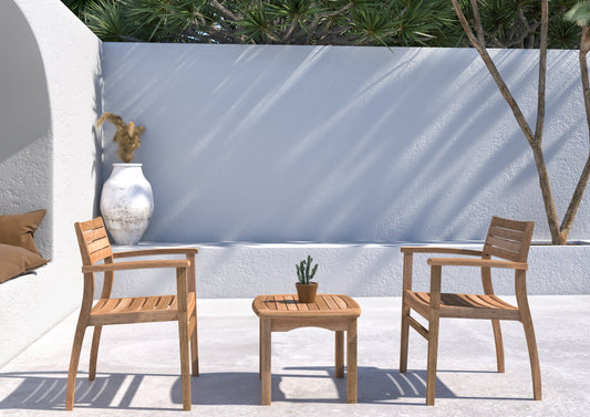 Teak wooden Intan Side Table with Ninia Chairs set in a minimalistic garden with white walls and greenery