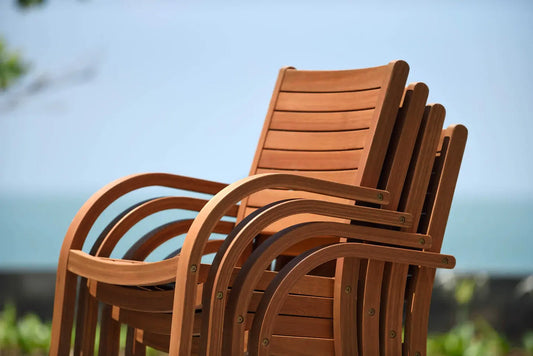 Four Catalina Stacking Wood Armchairs neatly stacked in a wabi sabi inspired outdoor setting.