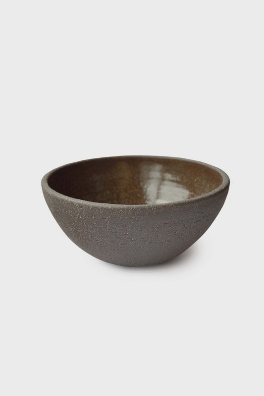 Handmade dark stoneware bowl with subtle texture and warm tones.
