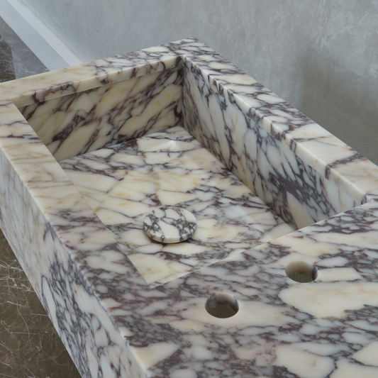 A Calacatta Viola marble bathroom sink with two holes, featuring intricate veining in white, cream, and brown tones.
