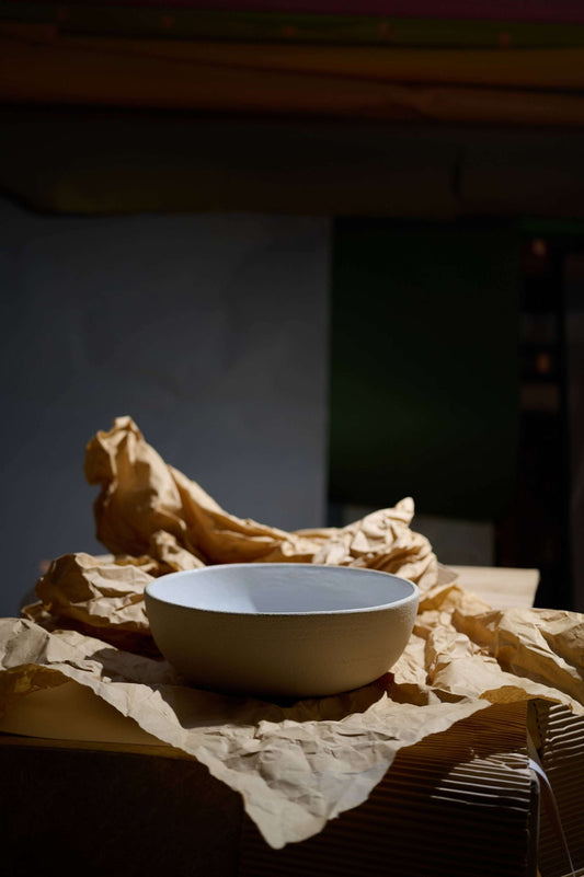A stone bowl amidst crumpled paper on a dark surface.
