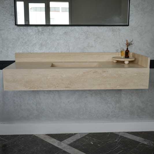 A rectangular travertine bathroom sink with an artisan design and natural beige color, mounted on a wall. The sink has a modern style with visible mineral veins.