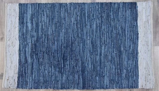 A navy blue natural leather and jute handmade rug placed on a light wooden floor.