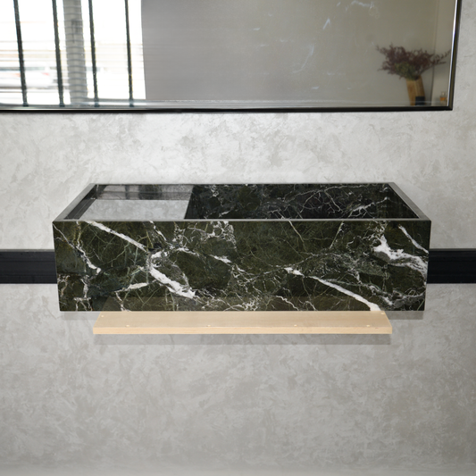 Green marble bathroom sink with white veining, mounted under a large mirror in a modern bathroom setting.