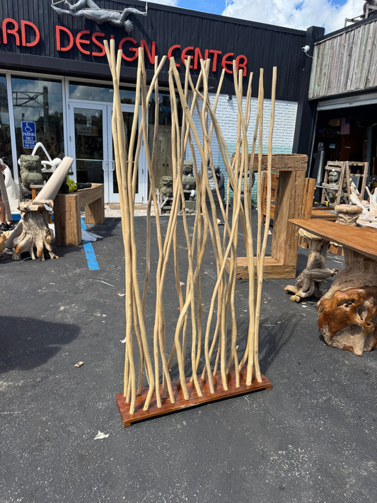Teak Branch Screen/Divider leaning against a building with various sculptures and furniture pieces in the background.