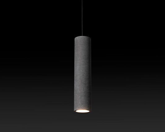 A tall, slender concrete pendant light with a light source inside, suspended against a dark background.