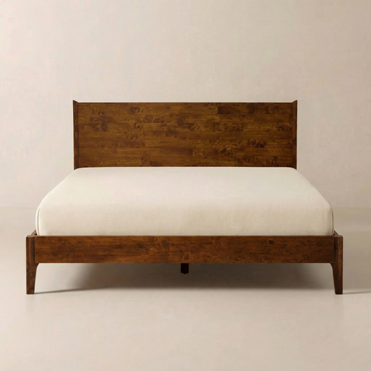 Wooden bed frame with a simple headboard and white mattress on a minimalist white floor and wall background.