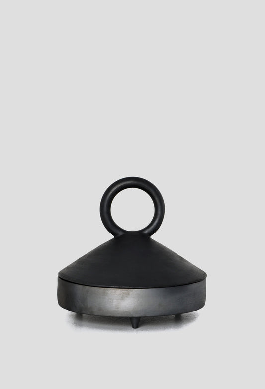 Black ceramic serving bowl with a matte finish and circular handle on a light grey background.
