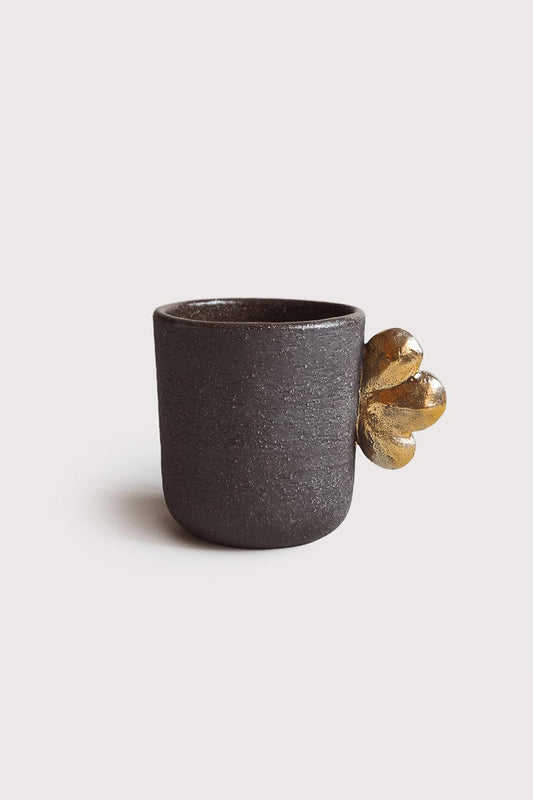 Handmade stoneware coffee cup "Pumpernickel" with gold leaf handle, dark brown textured surface against white background.