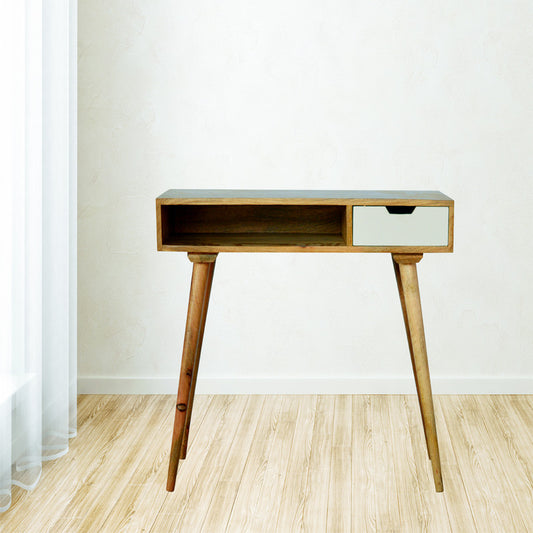 Modern wooden desk with a single drawer painted in white, light wood tones and simple legs, positioned in a minimally furnished room with light wooden flooring and sheer curtains.
