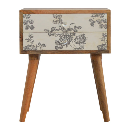 Two-tiered bedside table with floral screen printing in black and cream colors.