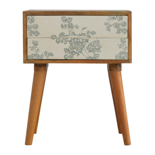 A two-drawer bedside table with floral screen print on cream background and wooden legs
