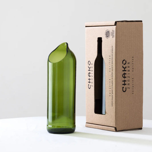 Modern green upcycled glass vase beside brown cardboard box, minimalist white background