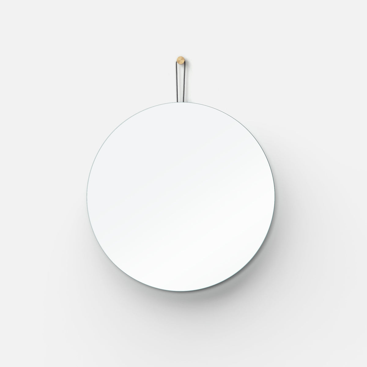 A circular mirror with a minimalist design attached to a metal wall mount.