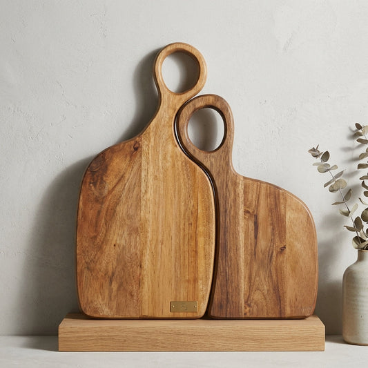 Two mango wood nesting boards with handle and smaller one inside, gold tag, against white wall.