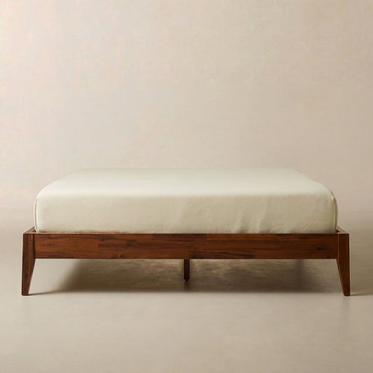 Single wooden bed frame with a light-colored mattress on a plain beige background.