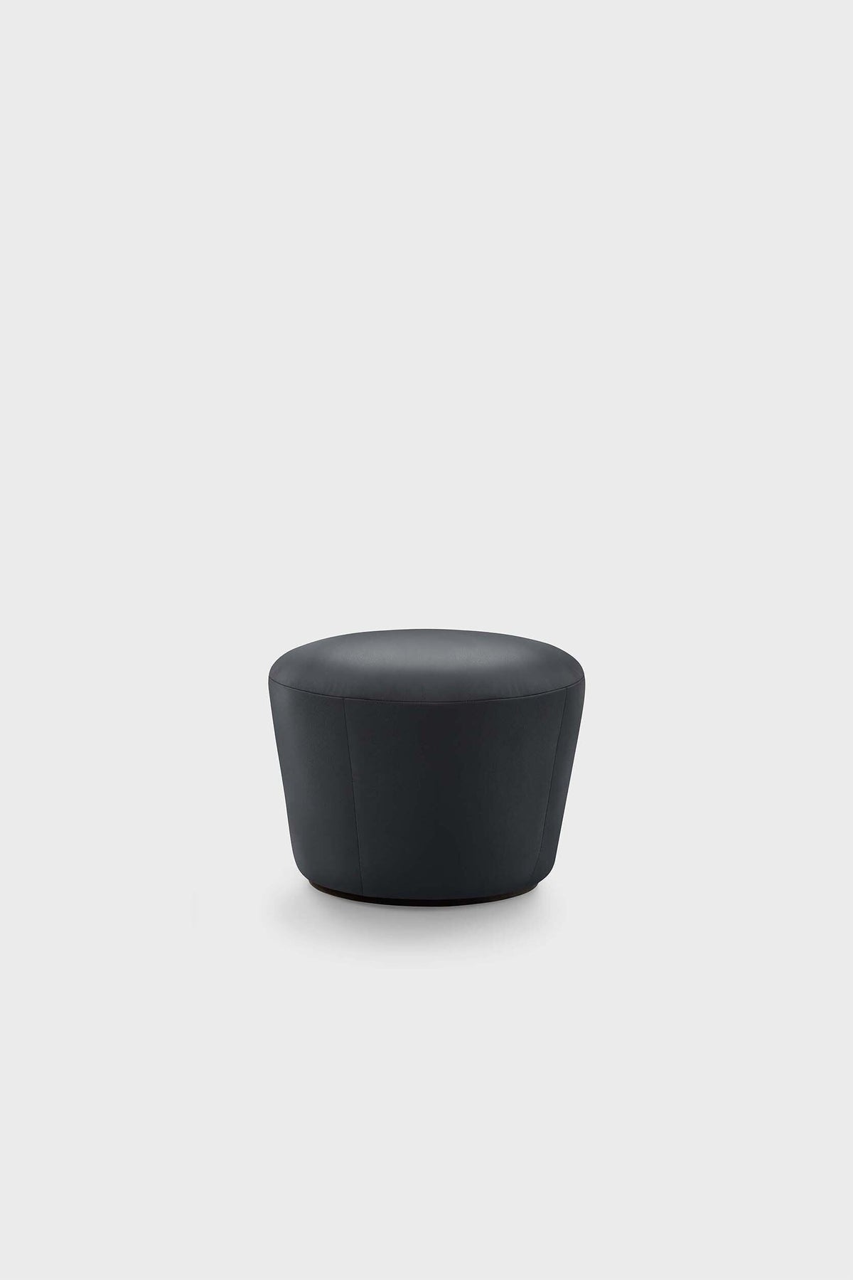 Naïve Pouf, round black leather stool on plain surface