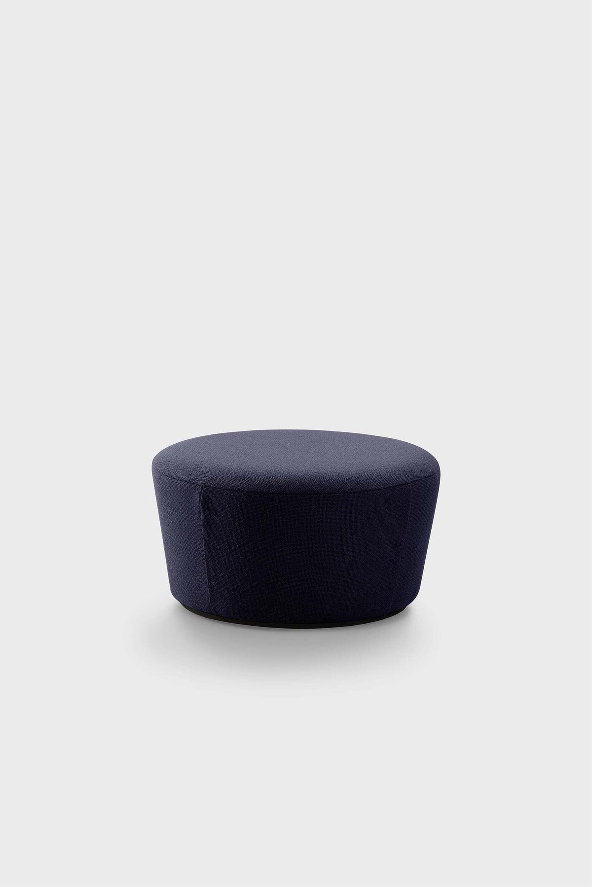 A dark blue pouf with a textured fabric sits on a plain surface.