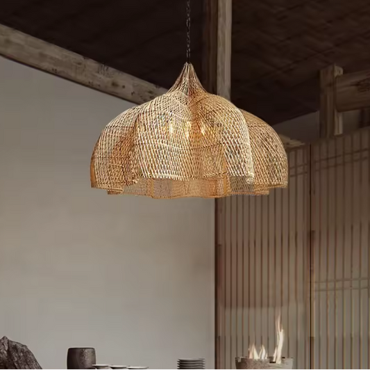 Wavy rattan lotus pendant light in a wabi-sabi home, hanging from the ceiling in an indoor setting with wooden elements and a fireplace in the background.