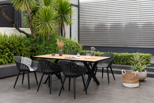 Black aluminum table set with 6 Nassau black chairs on a patio with greenery and plants, outdoor setting