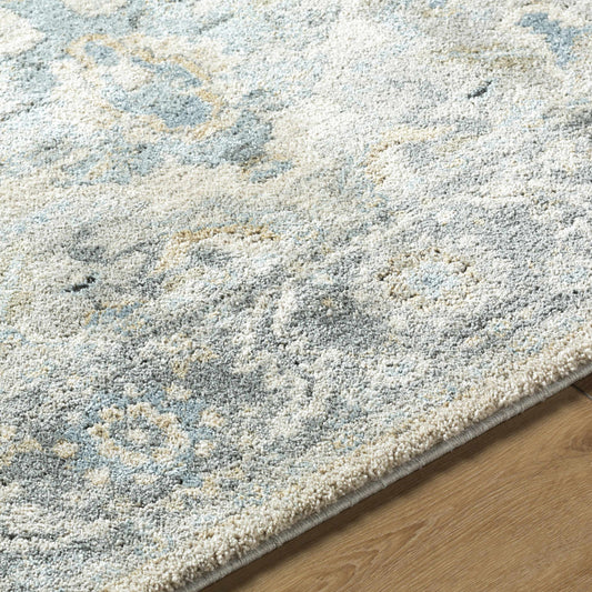A light gray thick area rug with an abstract floral pattern on a wooden floor, showing soft texture and detailed design.
