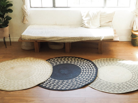 Three round mats in beige with geometric pattern in front of a futon on wood floors